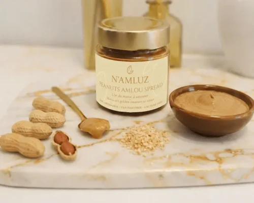 Pot de 300g d'amlou aux cacahuètes torréfiées. Sur une planche en marbre avec un bol et une cuillère.